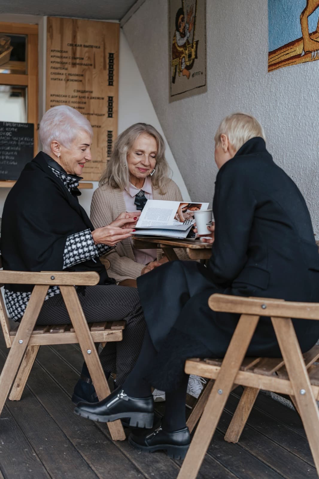 Drie mensen zitten in gesprek aan een tafel bij een café