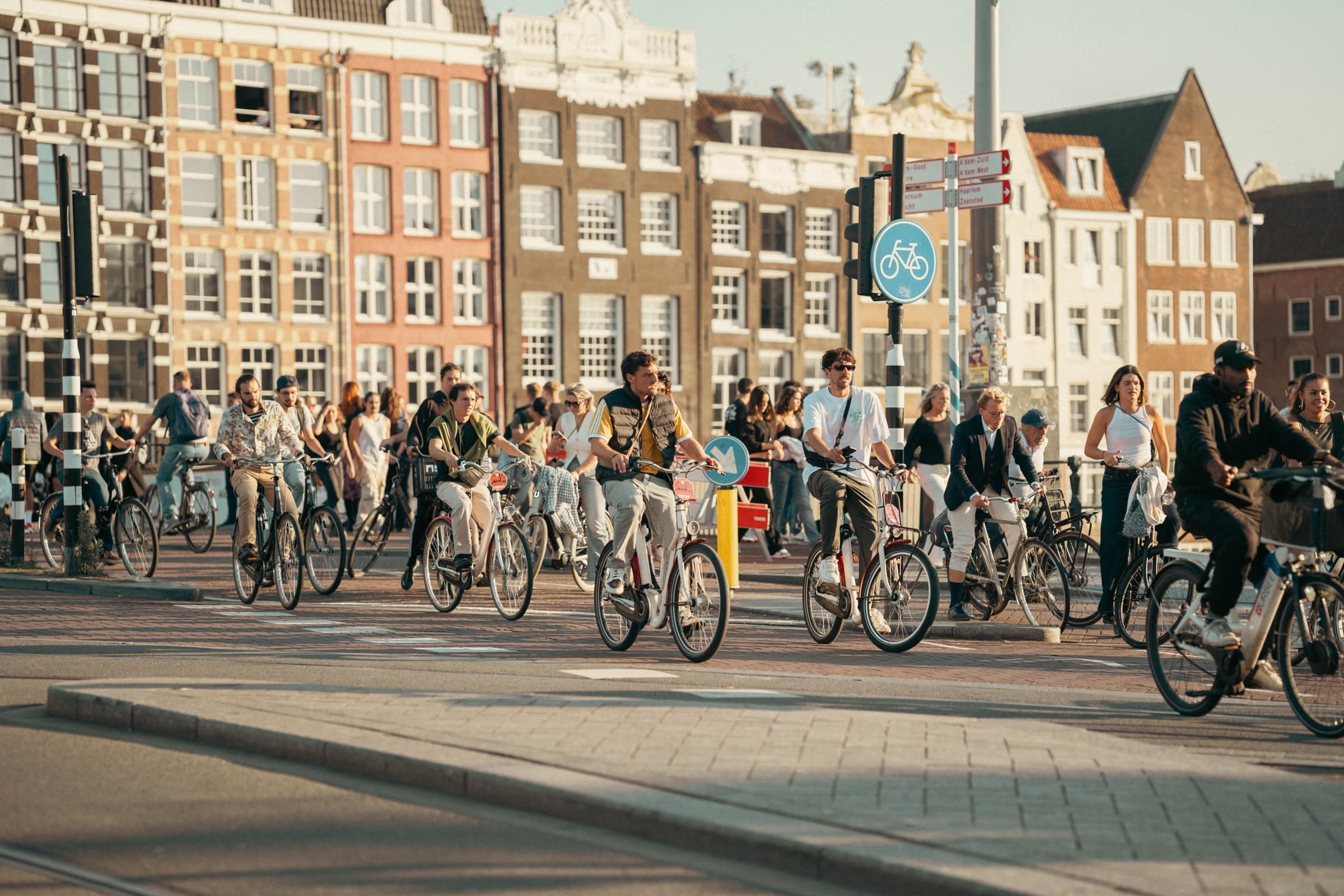Een zonnige Nederlandse straat vol fietsers voor grachtenpanden